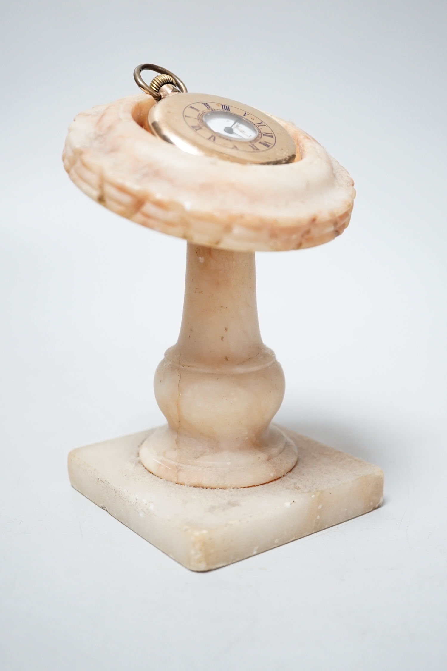 A gold plated pocket watch and carved alabaster stand, total height 14 cm